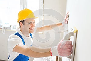 Smiling builder with grinding tool indoors