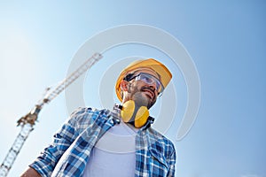 Smiling builder with hardhat and headphones