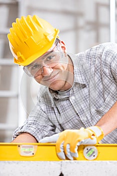 Smiling builder in a hardhat using a spirit level