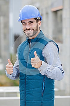 smiling builder in hardhats showing thumbs up outdoors