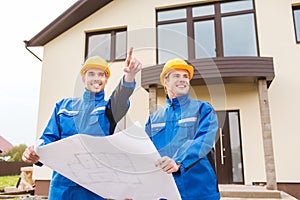 Smiling builders with blueprint pointing finger