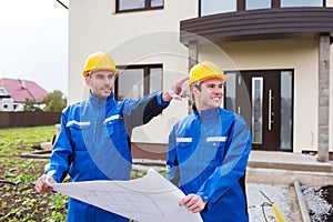 Smiling builders with blueprint pointing finger