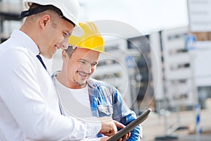 Smiling builders in hardhats with tablet pc