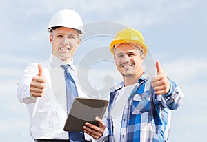 Smiling builders in hardhats with tablet pc