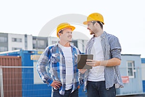 Smiling builders in hardhats with tablet pc