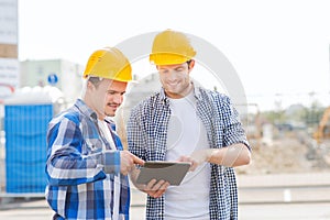 Smiling builders in hardhats with tablet pc