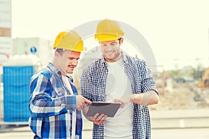 Smiling builders in hardhats with tablet pc