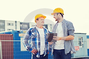 Smiling builders in hardhats with tablet pc