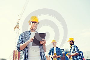 Smiling builders in hardhats with tablet pc