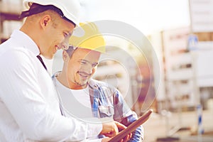 Smiling builders in hardhats with tablet pc