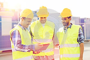 Smiling builders in hardhats with tablet pc