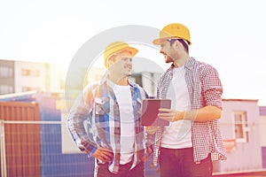 Smiling builders in hardhats with tablet pc