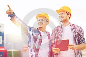 Smiling builders in hardhats with tablet pc