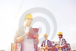 Smiling builders in hardhats with tablet pc