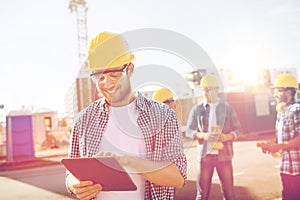 Smiling builders in hardhats with tablet pc