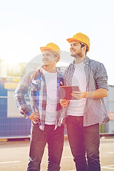Smiling builders with tablet pc outdoors