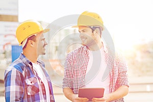 Smiling builders with tablet pc outdoors