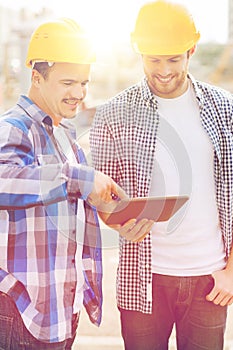 Smiling builders with tablet pc outdoors