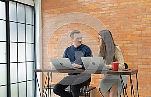 Smiling business blonde, white couple people working from home and talking together with computer notebook laptop and coffee on