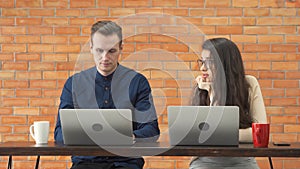 Smiling business blonde, white couple people working from home and talking together with computer notebook laptop and coffee on