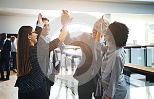 Smiling business colleagues high fiving each other in an office