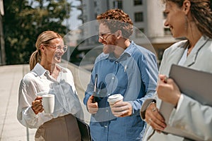 Smiling business colleagues talking and laughing during break time outside of office