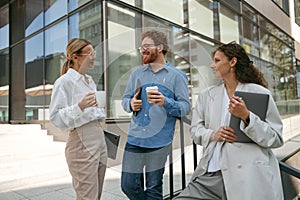 Smiling business colleagues talking and laughing during break time outside of office