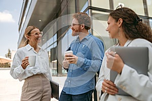 Smiling business colleagues talking and laughing during break time outside of office