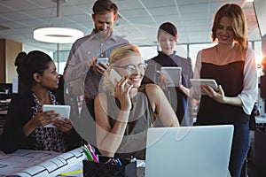 Smiling business colleagues using mobile phones and digital tablets together