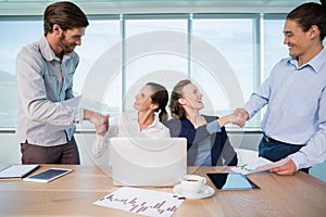 Smiling business executives shaking hands with each other in conference room