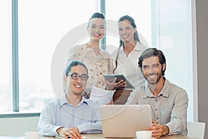 Smiling business executives using laptop and digital tablet in conference room