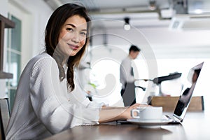 Smiling Business girl working with laptop. Happy Asian business woman using computer at coffee cafe. young people with laptop