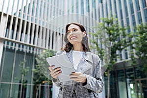 Smiling Business Lady Using Tablet Computer Standing In Urban Area