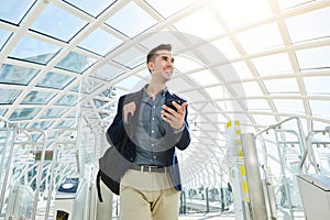 Smiling business man by airport turnstile with cellphone