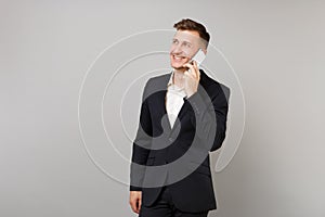 Smiling business man in classic suit looking aside talking on mobile phone conducting pleasant conversation isolated on
