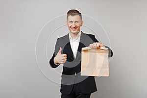Smiling business man hold brown clear empty blank craft paper bag for takeaway mock up isolated on grey background