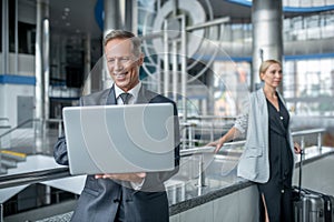 Smiling business man looking at laptop and colleague