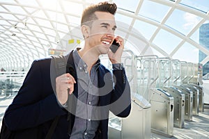 Smiling business man on phone walking by turnstile