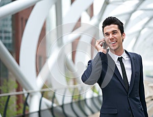 Smiling business man talking on mobile phone in the city