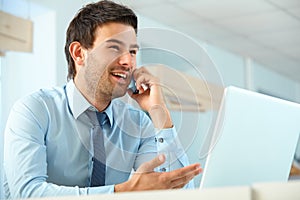 Smiling business man talking on mobile phone in a office