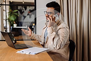 Smiling business man talking on mobile phone while working in office