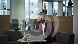 Smiling business man working office looking laptop screen. Manager drinking tea