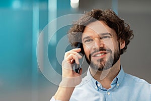 Smiling business man working and talking on phone at office