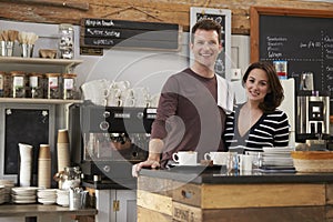 Smiling business owners behind the counter of their cafe photo