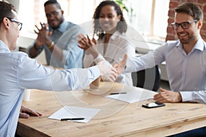 Excited employees handshake at meeting after successful negotiat