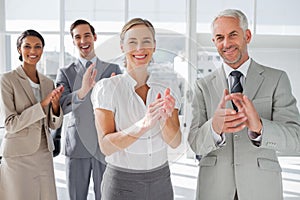 Smiling business people applauding together