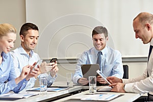 Smiling business people with gadgets in office