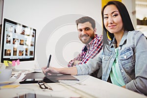 Smiling business people with graphic tablet at desk