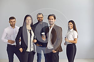 Smiling business people office workers team standing with coffee and documents and looking at camera