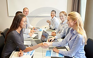 Smiling business people shaking hands in office